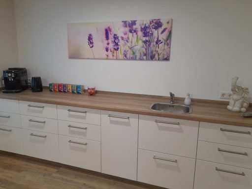 Küchenzeile Moderne Küchenzeile mit Holzarbeitsplatte, weißen Schränken, Wandbild mit Lavendelmotiv.