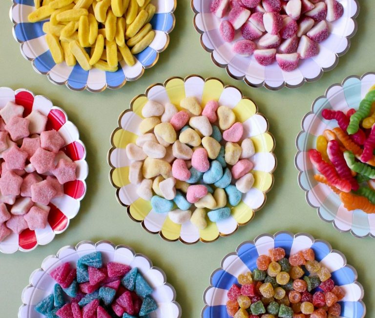 Suchtauflösung Süßigkeiten Bunte Süßigkeiten auf weißen Tellern, angeordnet in verschiedenen Formen und Farben.