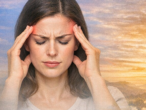 Workshop Migräne Frau mit Kopfschmerz, die sich die Schläfen hält. Im Hintergrund Sonnenuntergang.