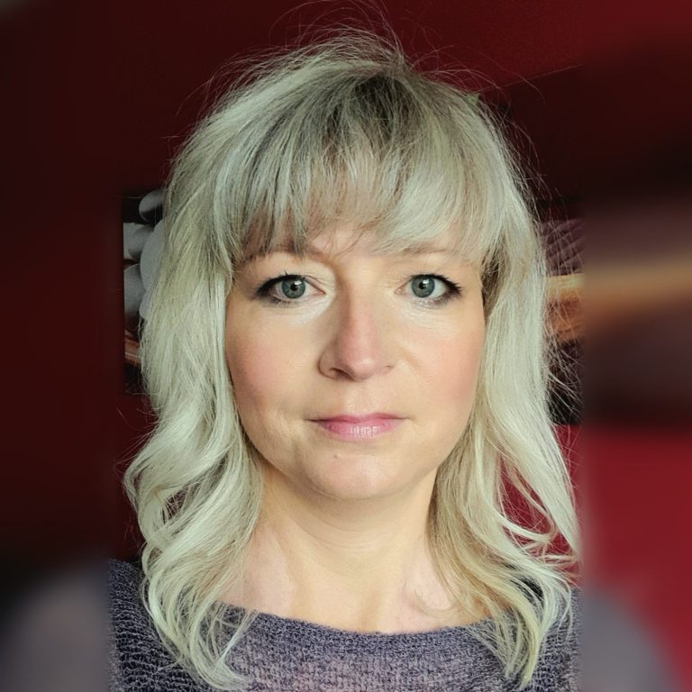 Daniela Gaßmann Frau mit blonder Frisur vor dunkelrotem Hintergrund